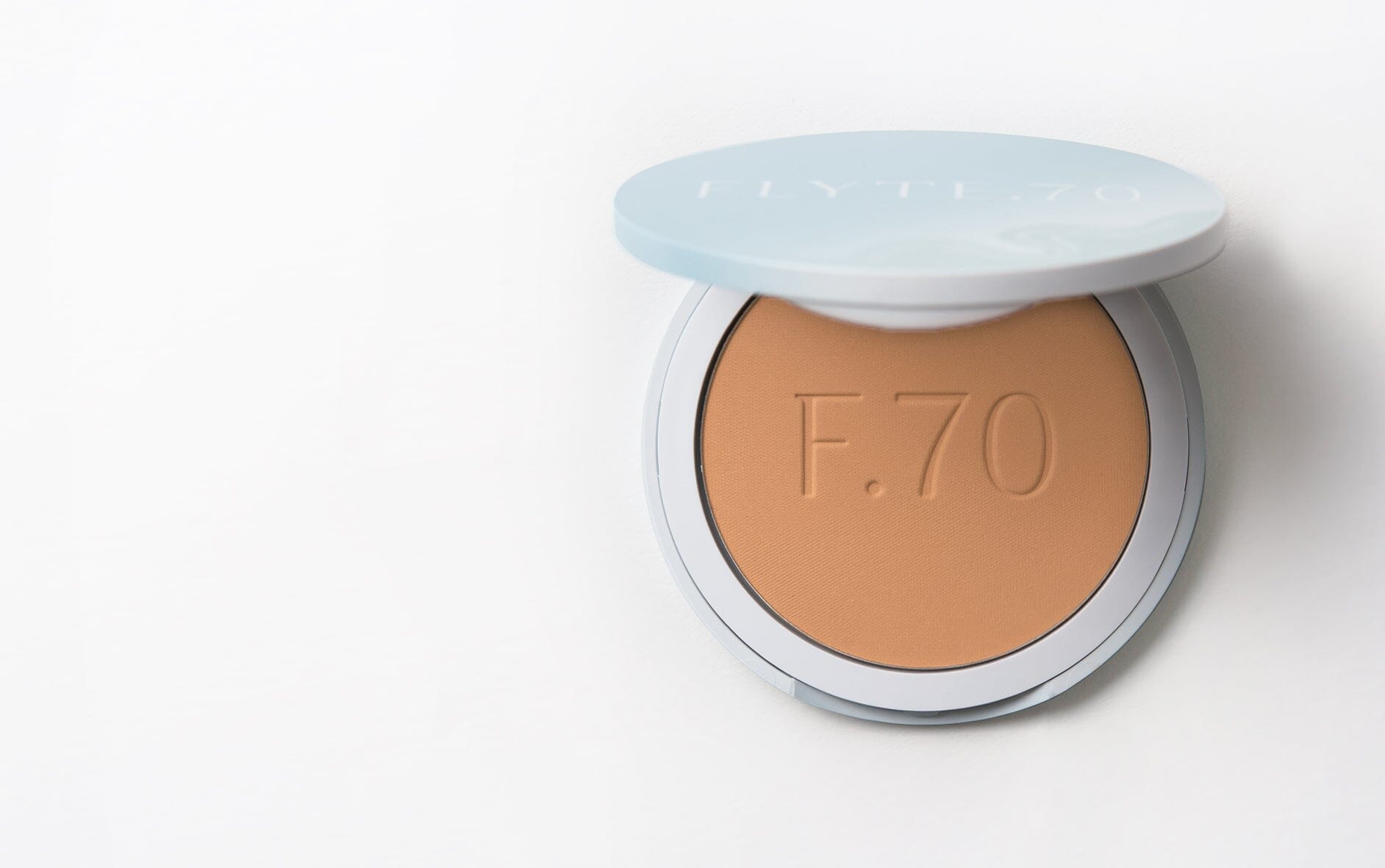 Compact of finishing powder in warm apricot and beige hue